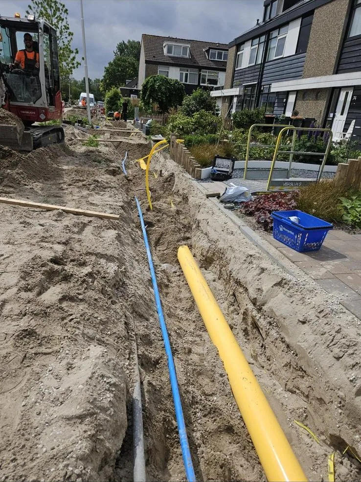 Open sleuf met leidingen langs woningen