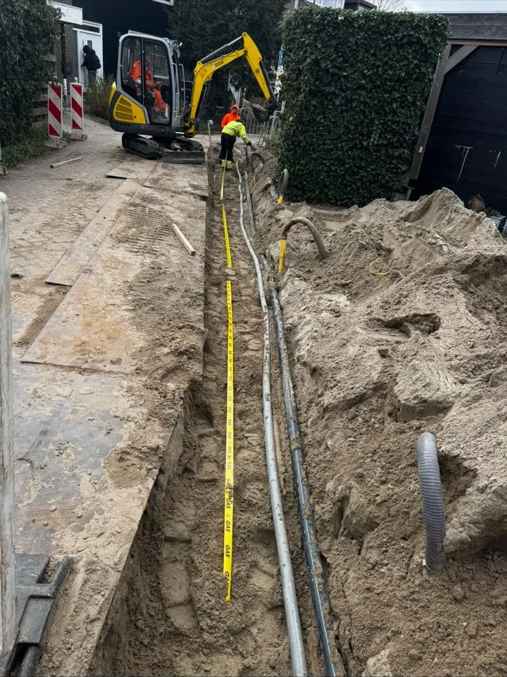 Minigraver graaft een sleuf voor een kabeltracé