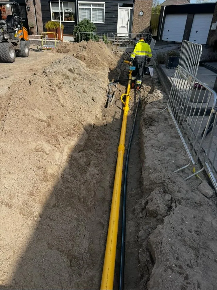 Medewerker in hi-vis kleding werkt in een open sleuf